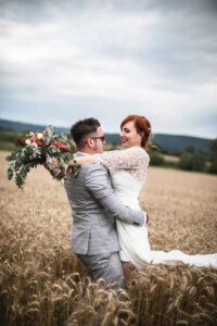 Bride and groom embracing in a field on they weddingday